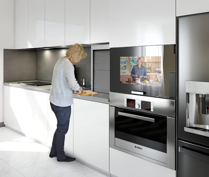 A woman is chopping something on a countertop with a kitchen TV inset on an oven.