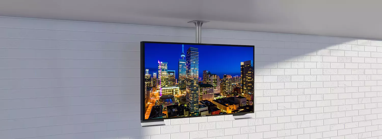 White brick wall with a ceiling-mounted outdoor TV shows a busy city.