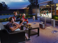 A group of friends joyfully watching kickboxing on an outdoor TV in their backyard.