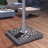 Black river stones base mount for outdoor TV with stainless steel pole on a wooden floor.