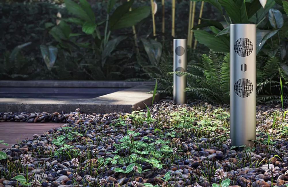 Two weather-resistant cylinder speakers in a garden.