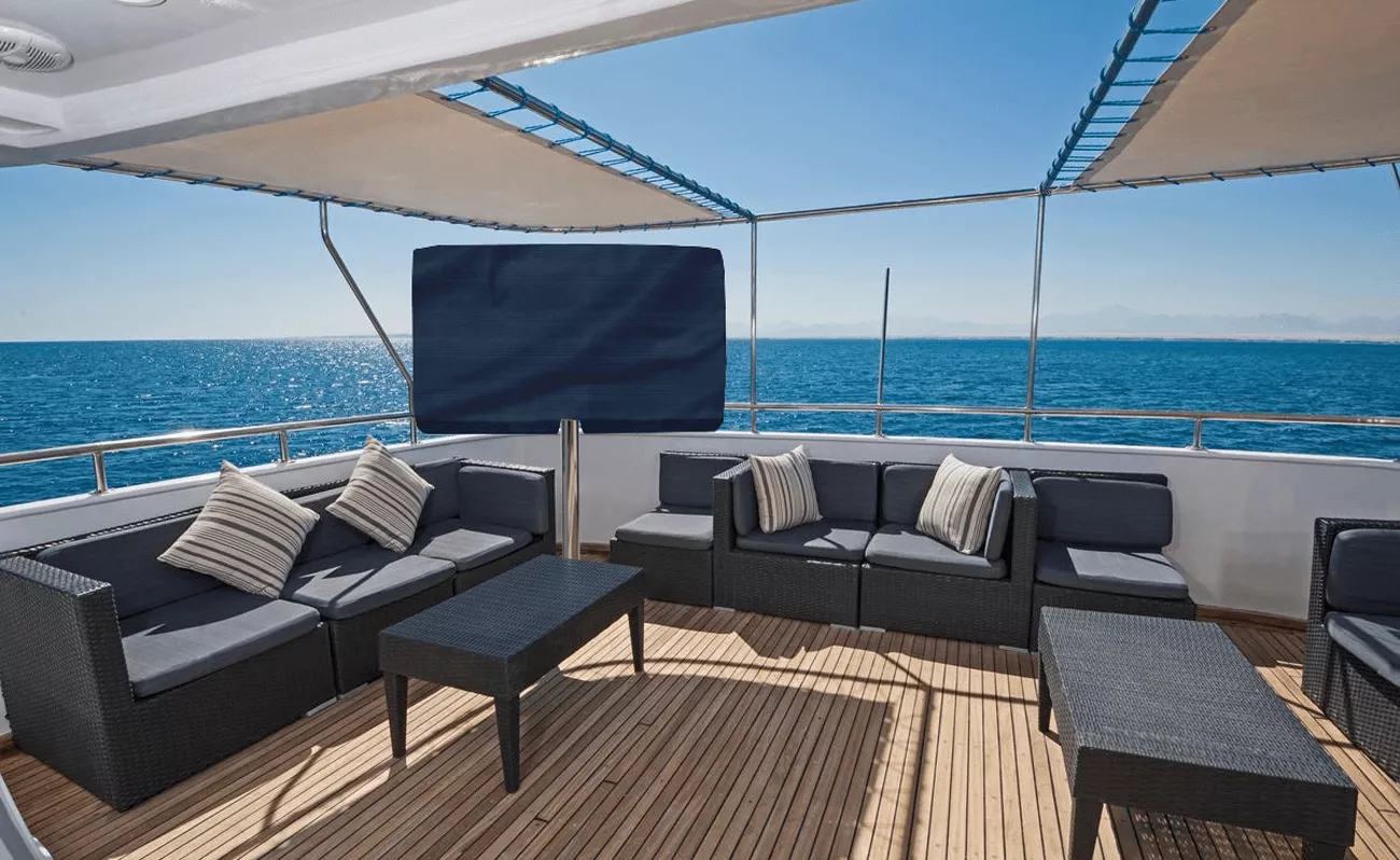 Luxurious yacht deck with elegant couches, tables, and cosmos outdoor TV with its sunbrella cover.