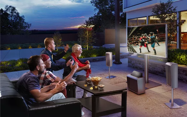 Group of peers watching on an outdoor TV with a sound-wave audio system in the backyard.