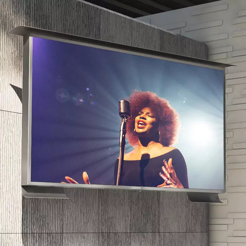 A woman singing displays on a wall-mounted outdoor TV.