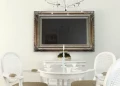 Miniatura de un hermoso TV espejo con un marco ornamentado, montado sobre una mesa de comedor en una habitación elegante.