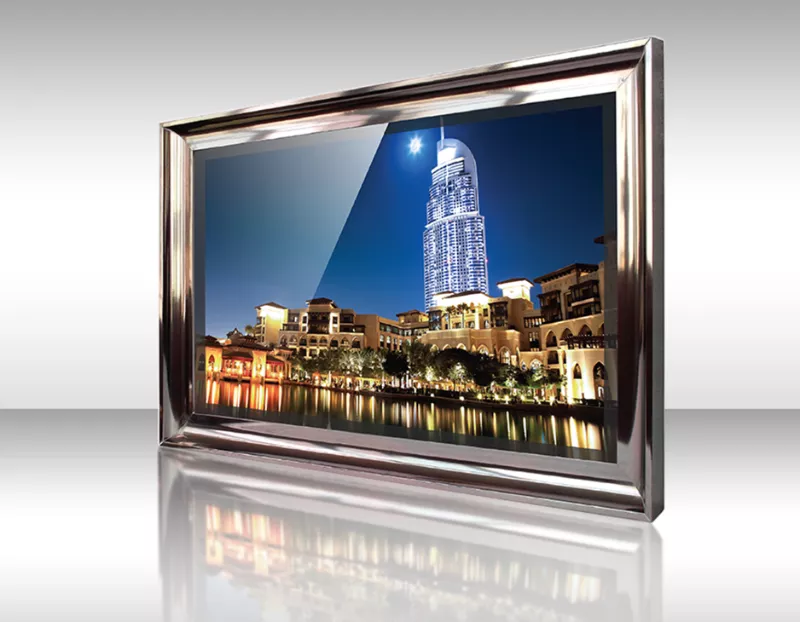 TV espejo con marco plateado mostrando paisaje urbano de noche con un edificio alto y reflejos en el agua.
