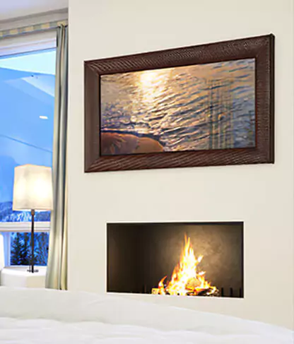 TV espejo con marco de cuero marrón montado sobre una chimenea con una ventana de vidrio.