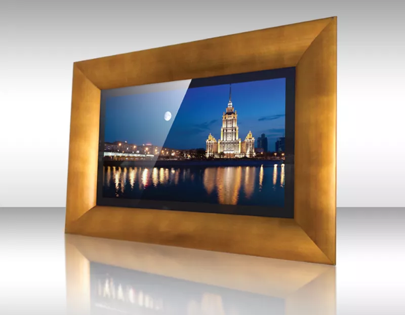 Televisor espejo enmarcado mostrando edificio iluminado junto al río de noche con reflejos en el agua.