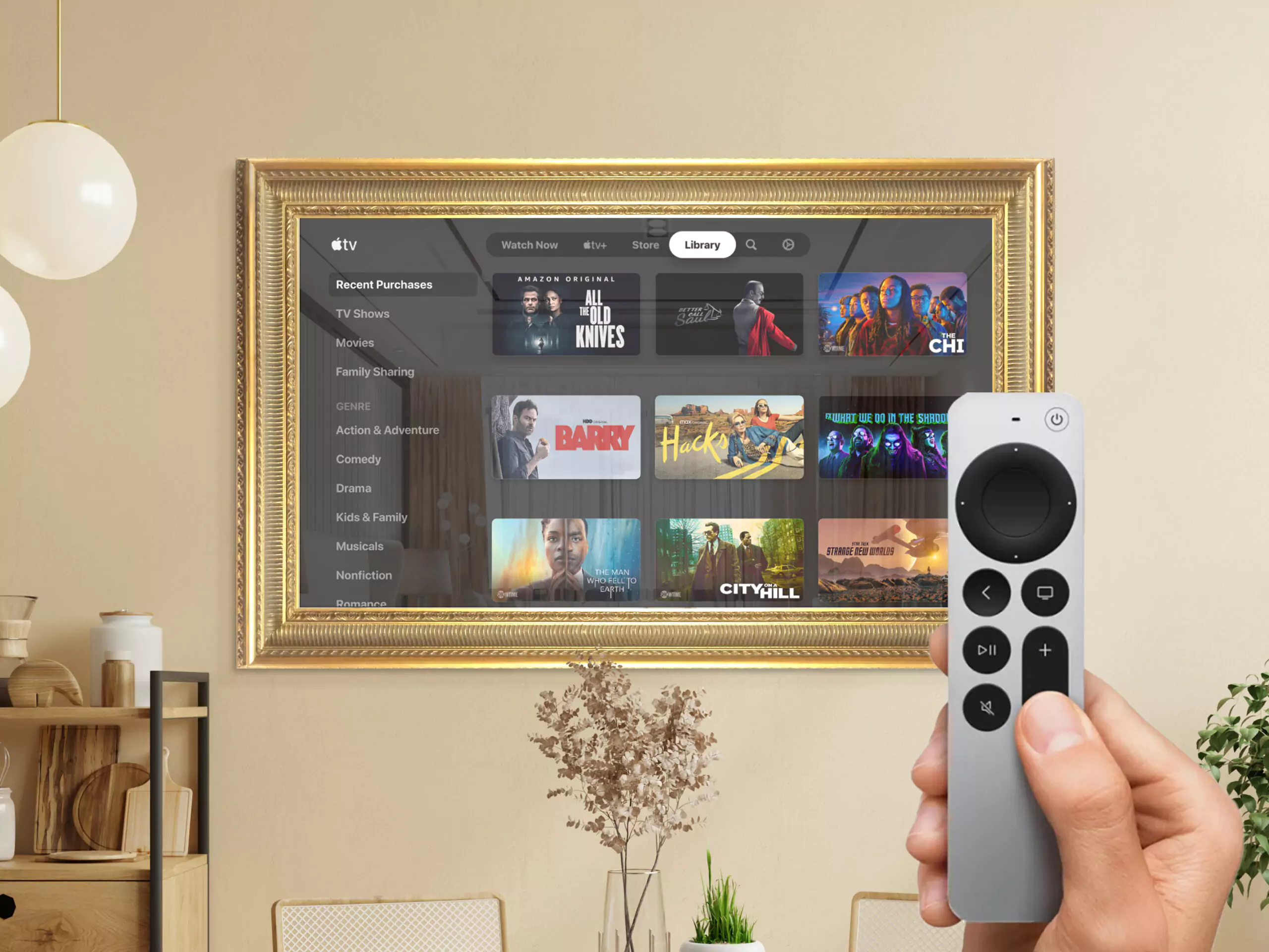 Un TV espejo con marco dorado instalado en una pared con una mano sosteniendo un control remoto.