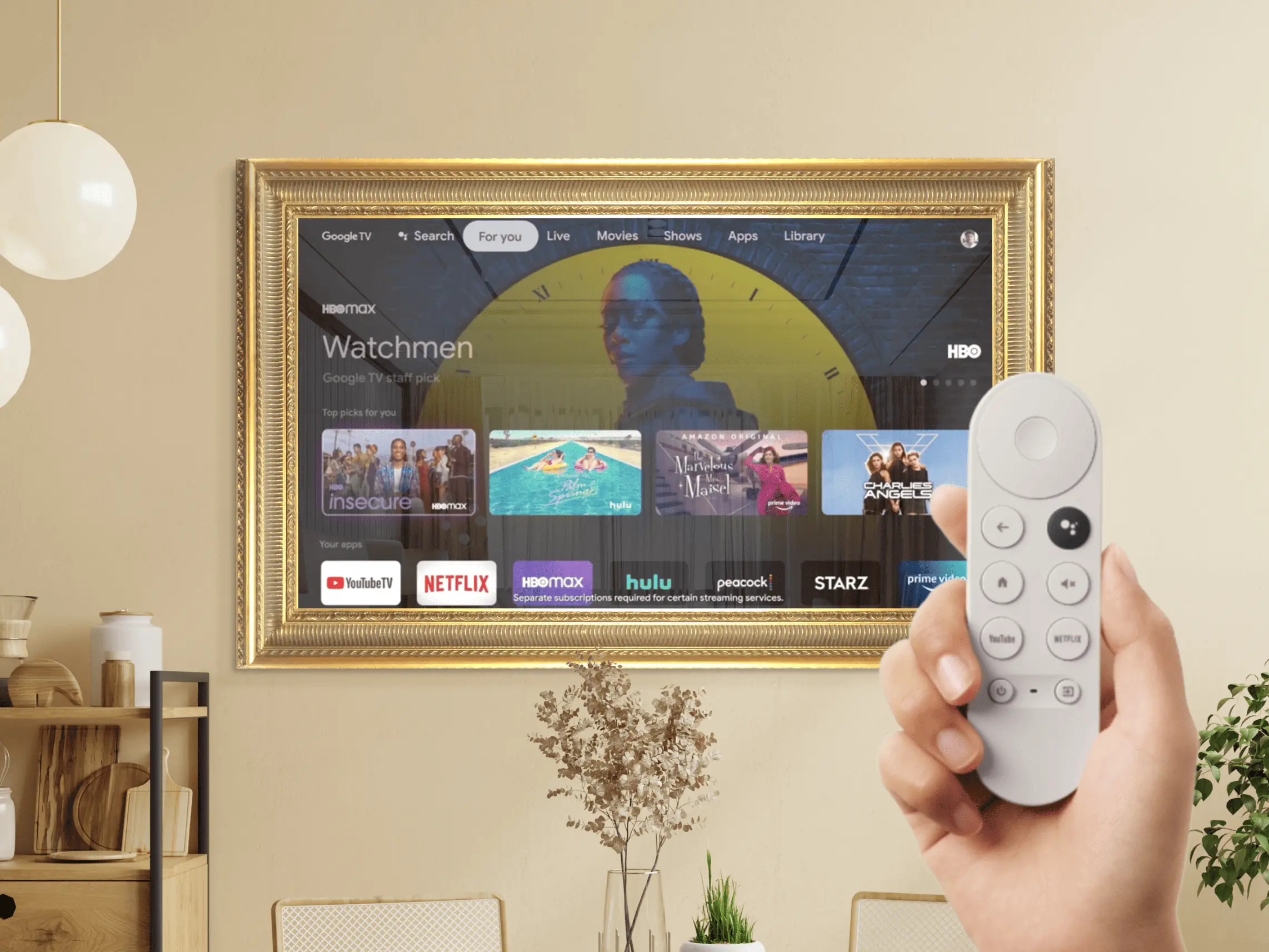 Un TV espejo con marco dorado colocado en una pared y manos sosteniendo un control remoto de Chromecast.