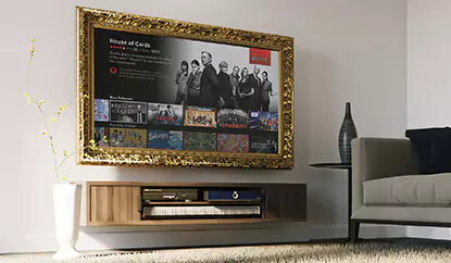 TV espejo con marco dorado sobre una pared blanca sobre un mueble de lado de madera en una sala de estar.