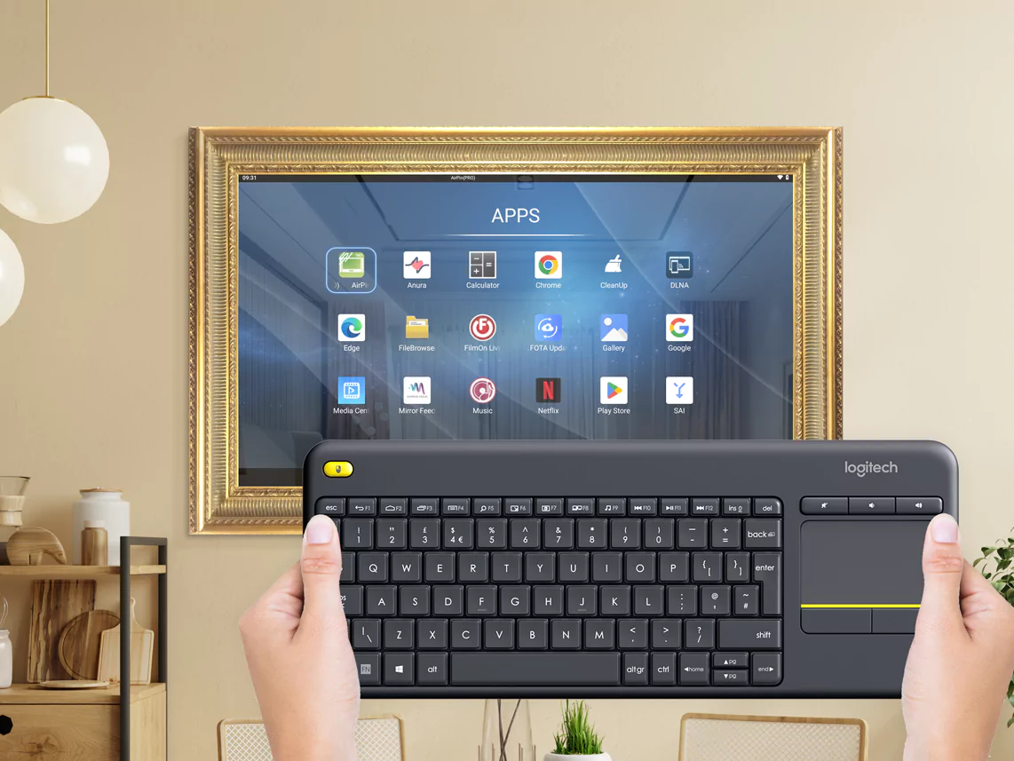 Un TV espejo con marco dorado colocado en una pared beige neutra con una mano sosteniendo un teclado.