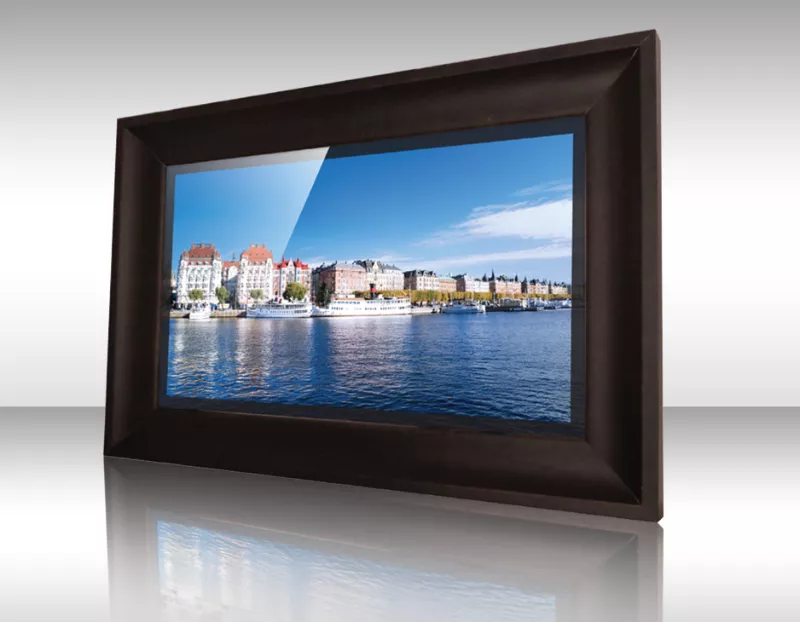 Televisor espejo con marco oscuro mostrando ciudad costera con edificios coloridos y cielo azul.