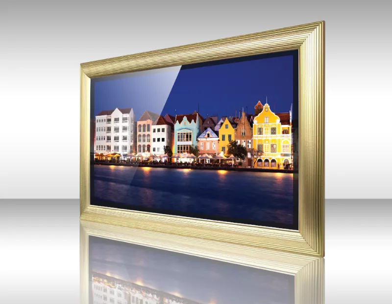 Televisor espejo con marco dorado Voiron muestra coloridos edificios frente al mar al atardecer.