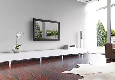 TV espejo inteligente montado en la pared sobre un mueble de lado completo en una sala de estar.