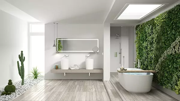 Tiny of bathroom with a bathtub, and a lighted mirror above the two lengthy oval sinks in Ajman.