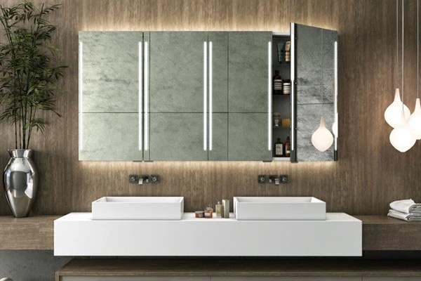 Grand Mirrors Cabinet mounted on a wooden wall above two granite sinks beside a plant in Ajman.