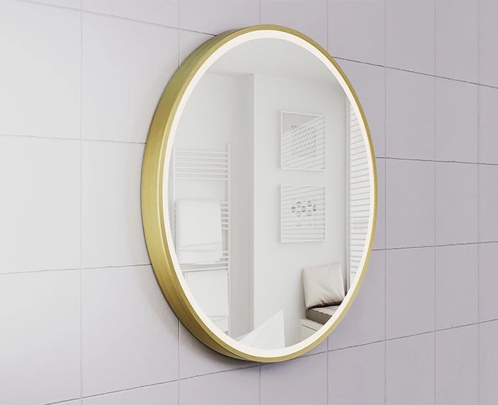A circular lighted mirror with a gold frame attached to a white tiled wall in Al Ain.