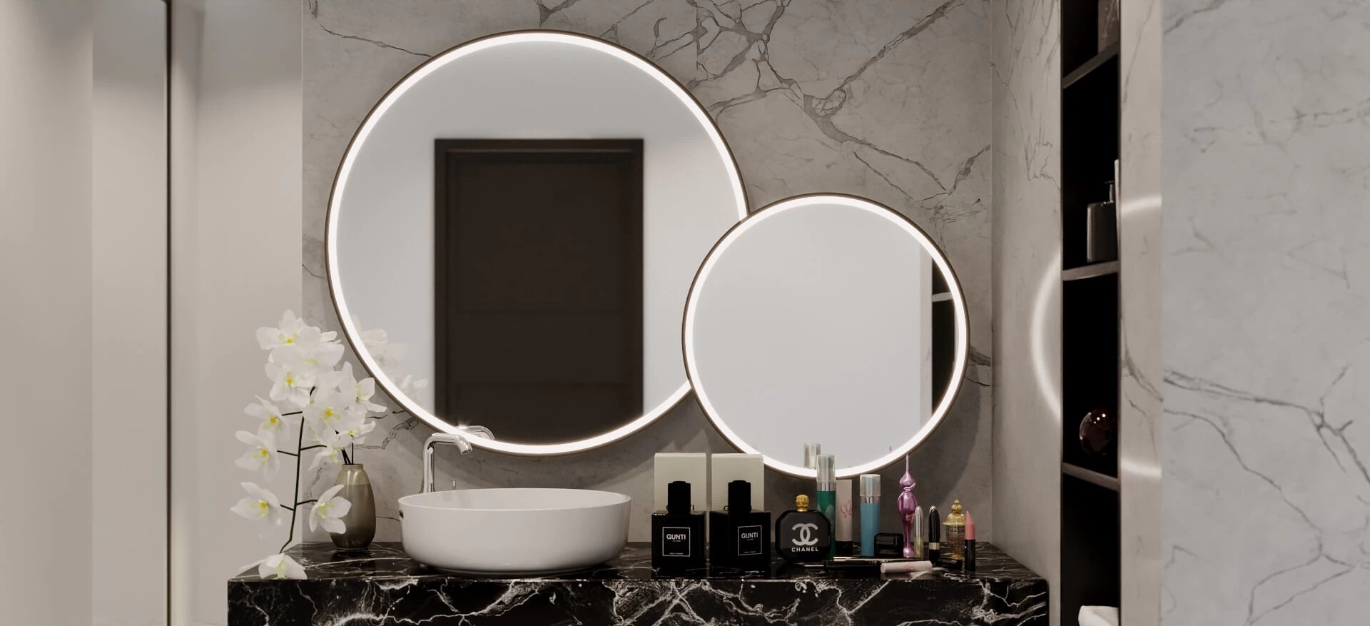 Two round lit mirrors mounted on a marble wall above a white bowl and beauty products in Al Ain.