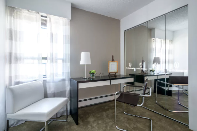 Tiny of comfortable office space features a white couch and mirror with led light logo from Bahrain.