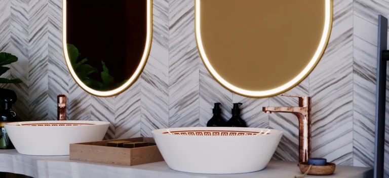 Two white basins with stylish patterns, copper faucets, and a pair of oval lit mirrors in Bahrain.