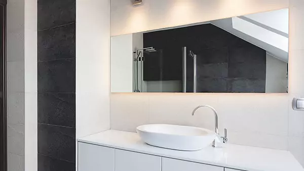 Small of single sink and a lit mirror set into a white wall in a stylish bathroom from Abu Dhabi.