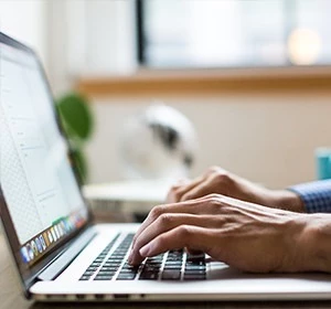 A person is typing on a laptop keyboard in a well-lit office environment in Dubai.