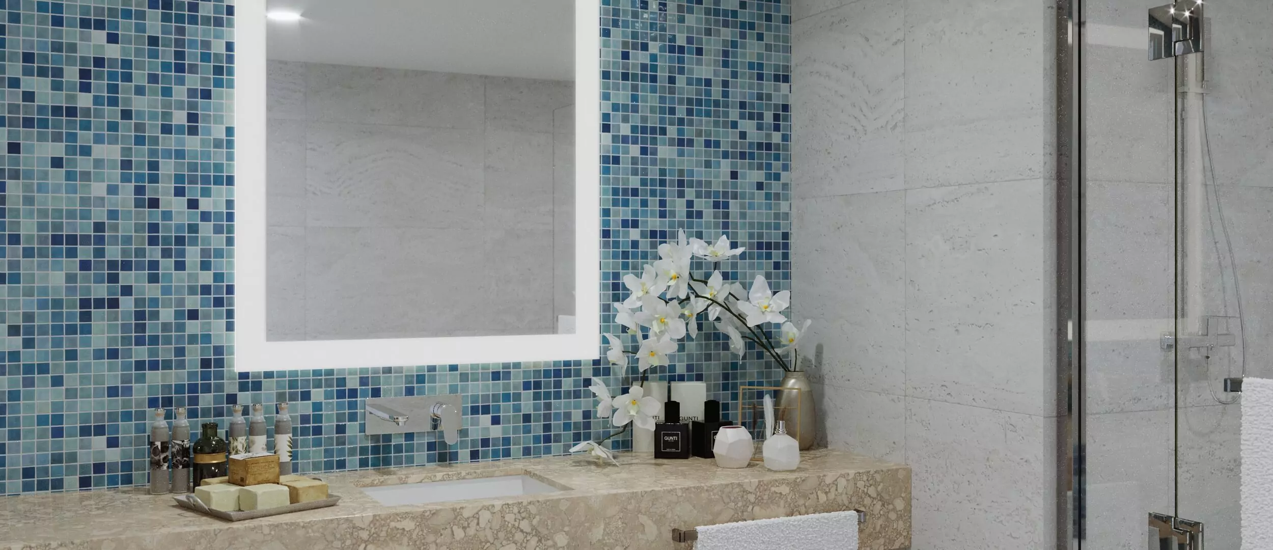 Grand mirrors lumiere above a tiled sink with bathroom products and an orchid in a vase in Dubai.