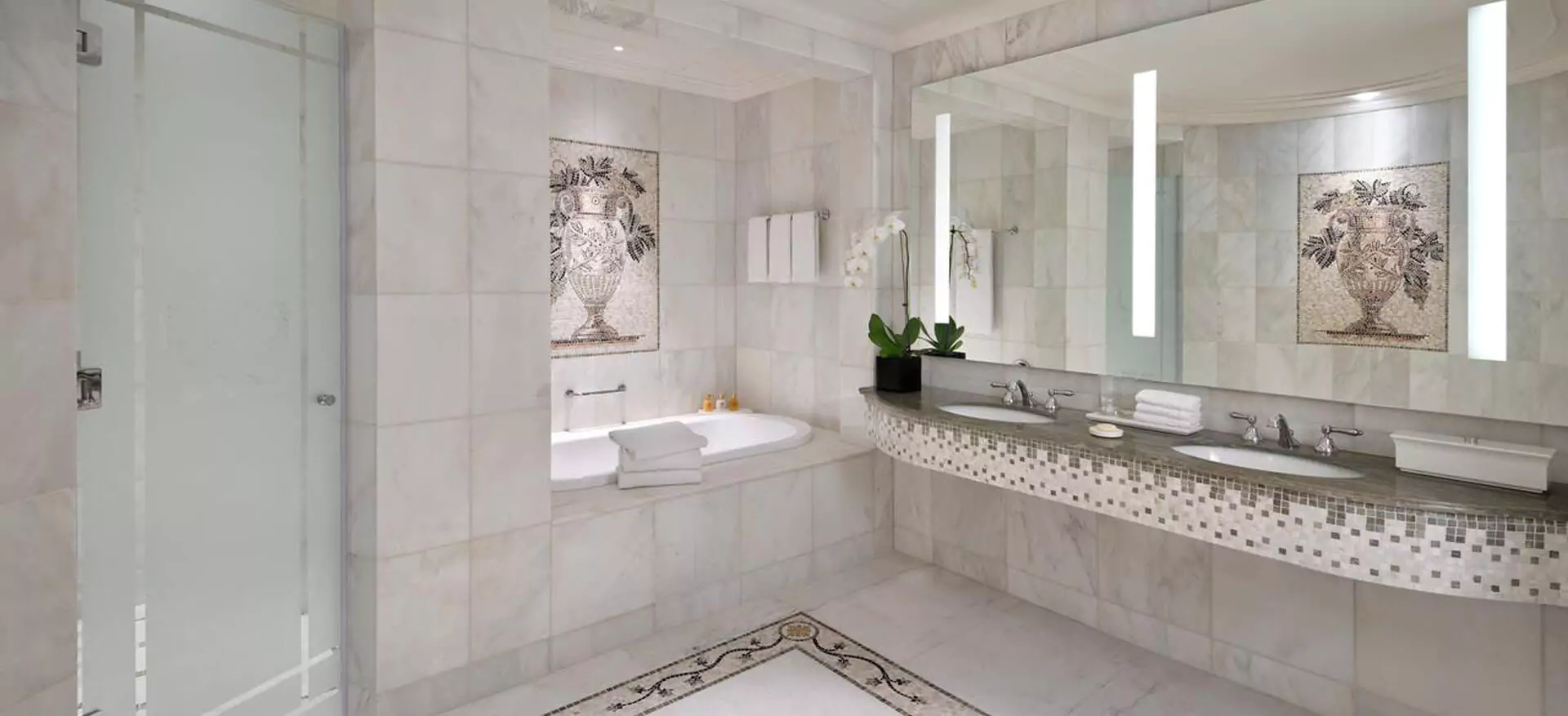 Luxurious classic designed bathroom with a bathtub, a glass door, and a lighted mirror in Dubai.