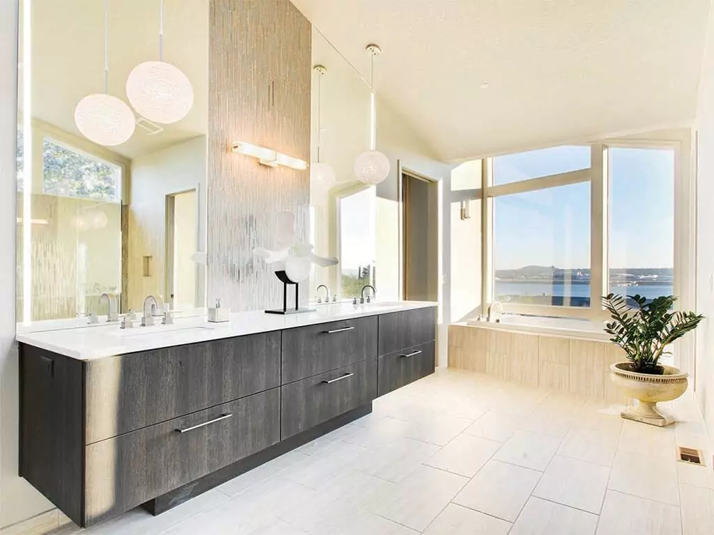 Classy bathroom in Dubai with two lighted mirrors above a wooden cabinet with marble countertop.