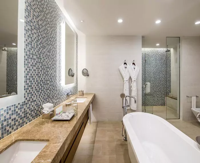 Fancy bathroom with a bathtub, shower room, and a sink with a lighted mirror in Abu Dhabi.