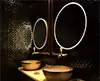 Tiny of Kuwait circular luxury LED mirrors attached to a black mosaic wall with basins and faucets.