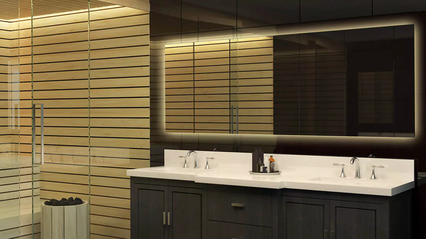 A backlit mirror is mounted on a glass wall in an elegant, dimly light bathroom from Sharjah.