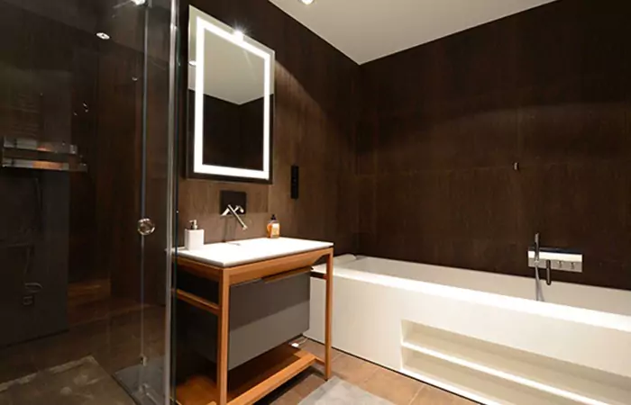 Fancy bathroom in Saudi Arabia featuring wood-paneled walls with luxury makeup mirror and a sink.