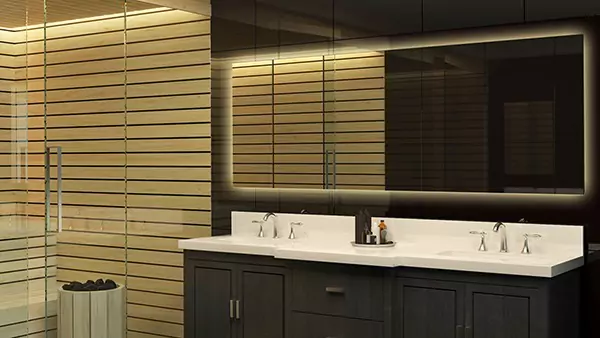 Icon of a backlit mirror is mounted on a glass wall in an opulent, dimly light bathroom from Oman.