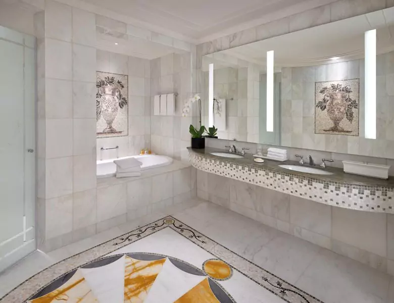 Luxury vanity mirror with lights, a double sink below, and a bathtub at the side in Oman.