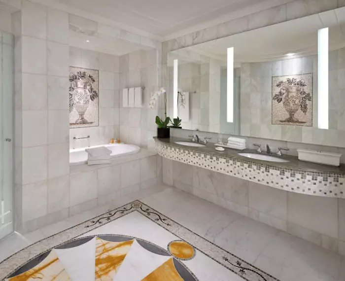 Bathroom with a marble wall in grid stacked pattern mounted with a custom lighted mirror in Oman.