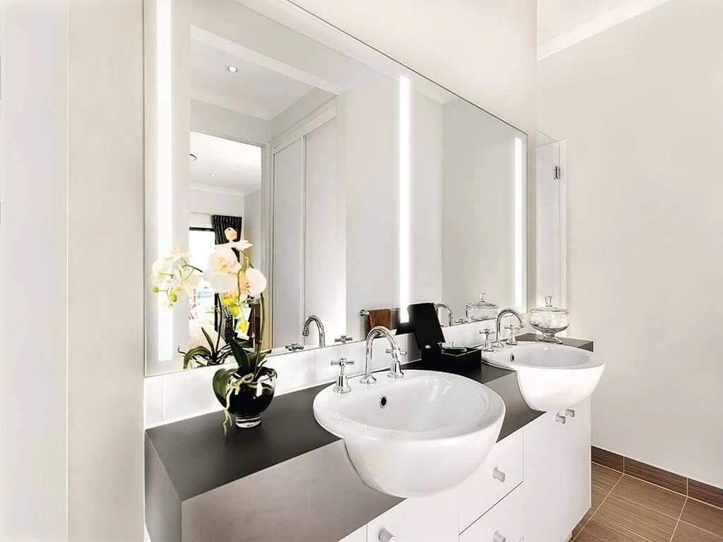 Bespoke lighted mirror with two white ceramic sinks below set on a concrete countertop in Qatar