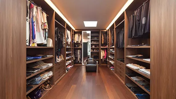 Mini of dressing room with cabinets full of hung and folded clothes and a vanity mirror in Qatar.
