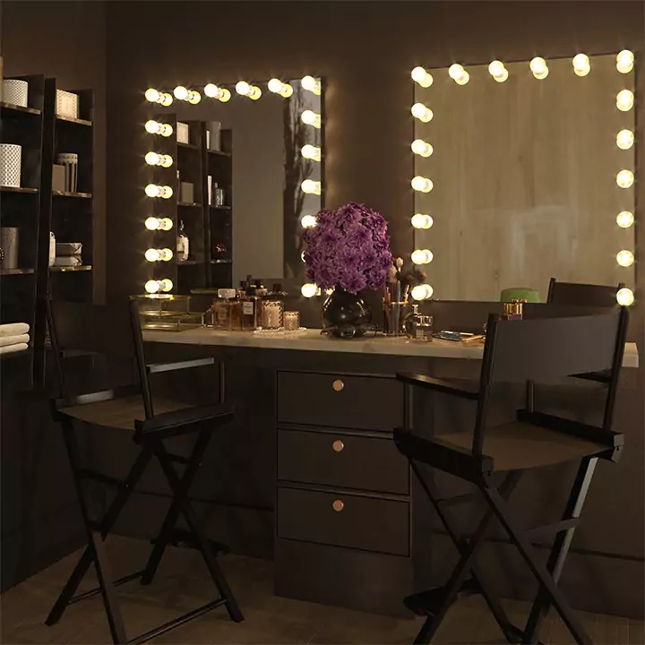 Above a vanity cabinet containing two canvas foldable chairs are two Hollywood mirrors from Qatar.