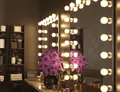Icon of Hollywood mirror on a countertop table, adorned with purple flowers and cosmetics in Riyadh.