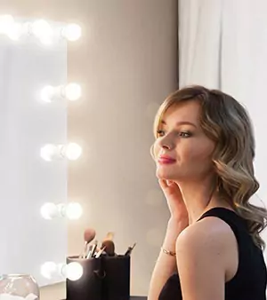 Thumbnail of a happy woman looks in a Hollywood mirror at herself from Saudi Arabia.