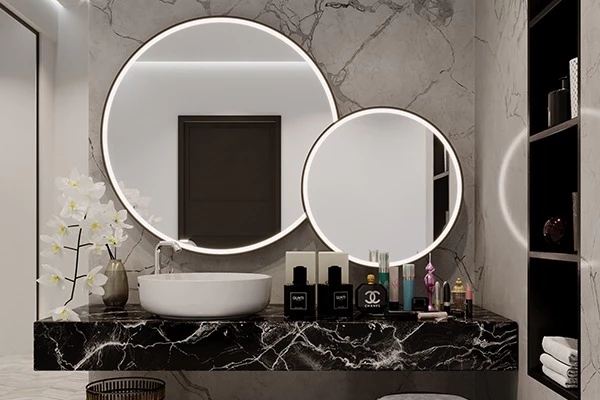 Circular lighted mirror with black aluminum frame above a white ceramic washbowl in Sharjah.