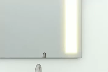 Other mirror with a low quality lighting mounted on a white concrete wall with a sink in Sharjah.