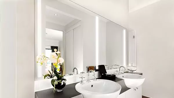 Thumbnail of lighted mirror with two white ceramic sinks below on a concrete countertop in Dubai.