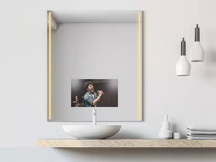 Warm light strips are built into a mirror TV above a lone white washbowl.