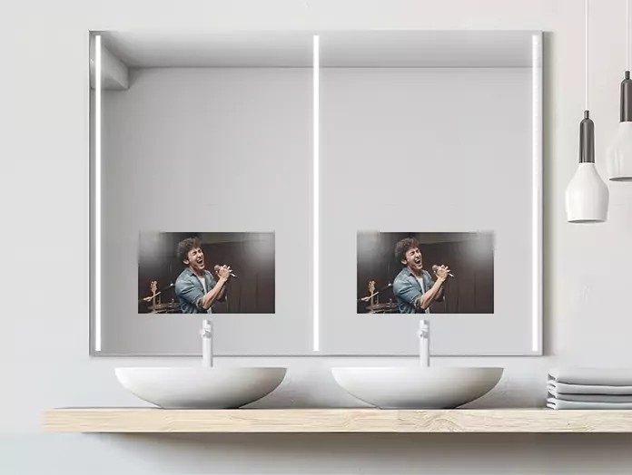 Double sink cool-lighted mirror TV is mounted on a white wall with a pendant lamp on the side.