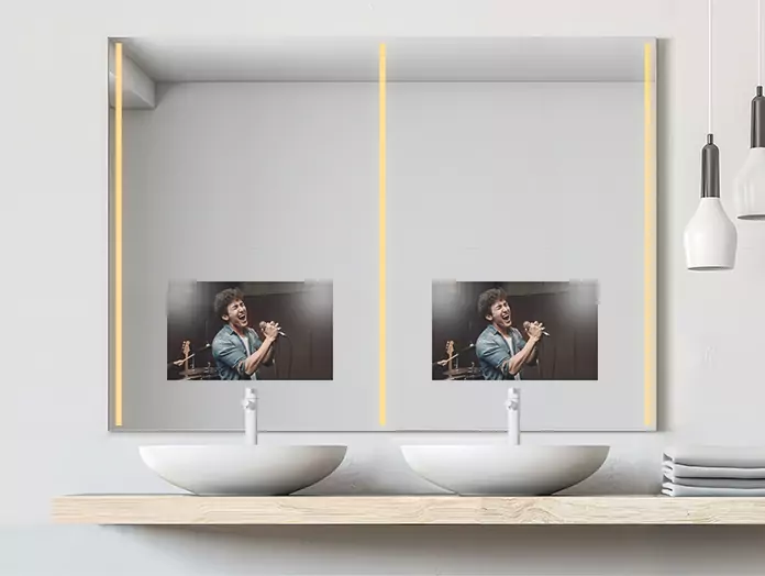 A double-sink warm-lighted mirror TV set on a white wall displays a singing man.
