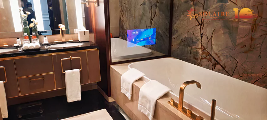 Baño elegante en Chitré con bañera profunda y espejo lujoso con TV sobre el área del tocador.