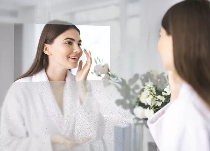 El reflejo de una mujer alegre en un televisor espejo antivaho.